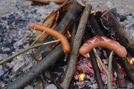 a sausage grilled on a camp fire