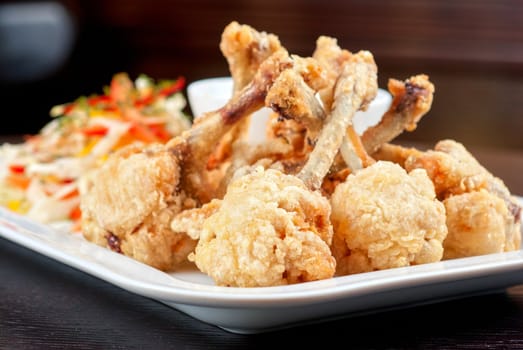 Fried chicken wings garnished with fresh vegetables with Teriyaki sauce
