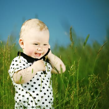 little boy in green grass call by phone