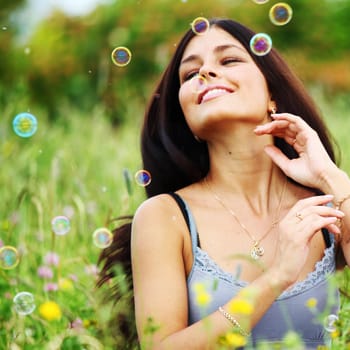  happy woman smile in green grass soap bubbles around