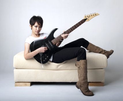 Punk Rockstar holding a guitar sitting on sofa.