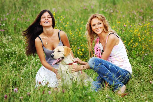 girlfriends and dog in green grass field