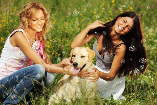 girlfriends and dog in green grass field