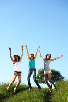 girlfriends jump in green grass field