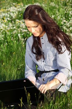 girl with laptop on green grass