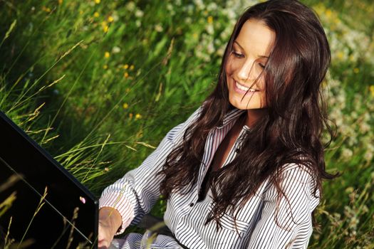 girl with laptop on green grass