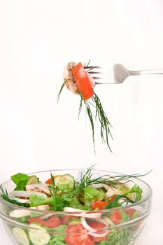 Closeup of tossed salad in a glass bowl with fork