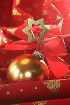 a gold Christmas ball with ribbon and star on red fabric