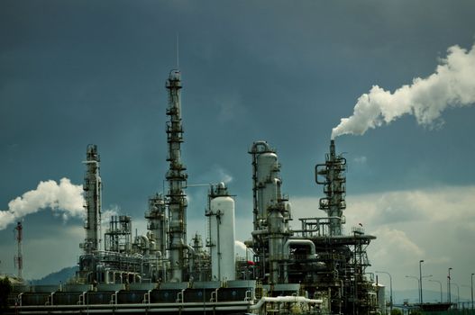 Oil refinery with smoke against moody sky