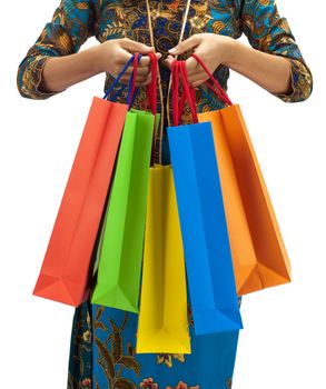 Woman in tradition Kebaya holding colorful shopping bag.