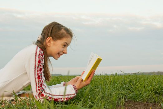 Teen girl reading a book at a field