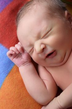 Newborn baby boy lying on a colorful blanket