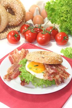 Rye bagel with salad, fried egg and bacon