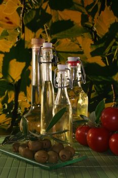 Olive oil with olive branch and fresh olives and tomatoes