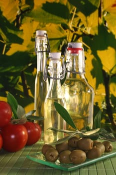 Olive oil with olive branch and fresh olives and tomatoes