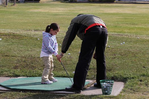 Young female golfer receiving a golf lesson