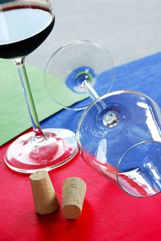 two wine glasses and corks over colorful background