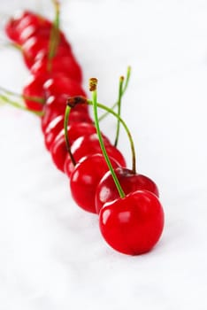 appetizing red fresh ripe cherries arranged in line over white background