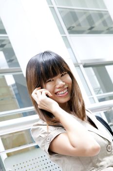 Asian Business woman on the phone outside office buiding.