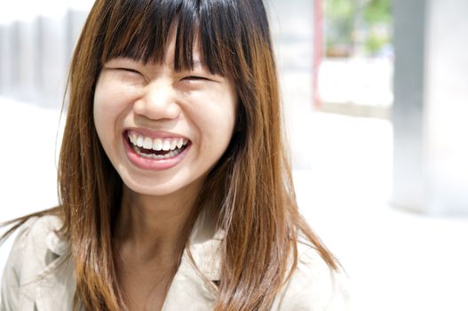 Asian female with her cheerful smile, outside modern building.