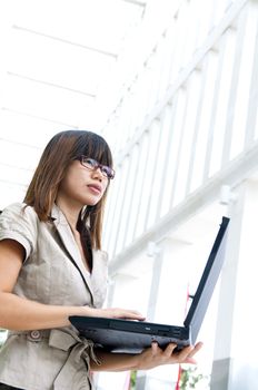 Asian female with laptop outside a modern building