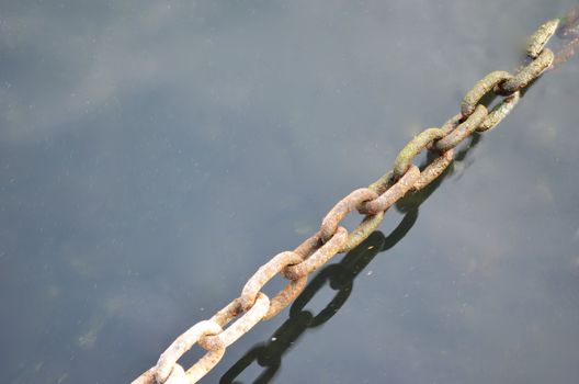 Rusty metal chain above and under water - with copy space