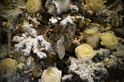 Christmas background, yellow, white and dark, with snowy pine branches, icy roses and lights