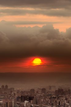 Sunset city scenery with red sun over buildings and clouds in Taipei, Taiwan, Asia.