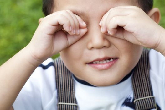 Four year old playful boy covers his eyes