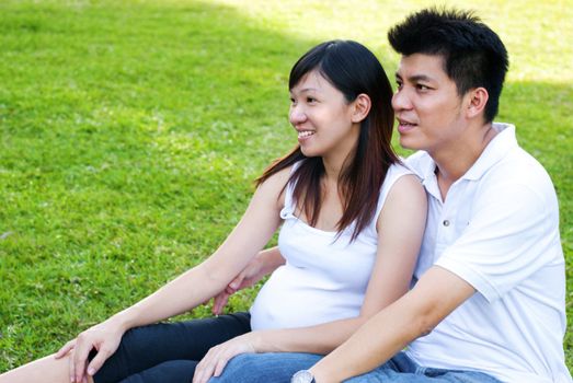 Husband and 8 months pregnant wife relaxing at outdoors.