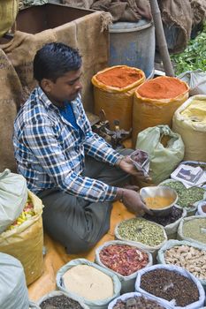 Man selling spices from a pavement stall in Old Delhi, India.