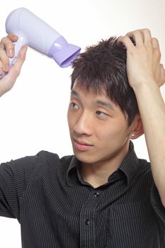 Concept image of metrosexual male featuring a young male using a hair dryer to fix his hair nicely