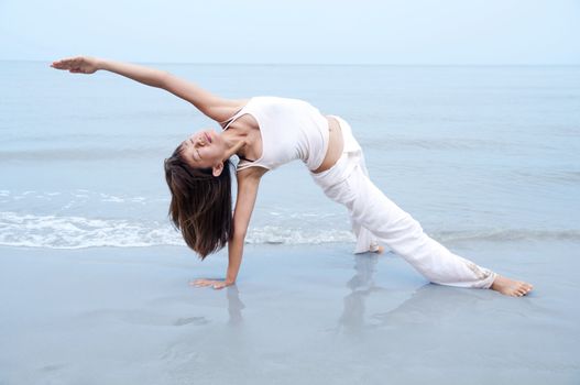 Woman practising Yoga(Gate Pose) on the beach.