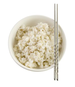 A bowl of cooked brown rice, in an Asian style bowl, with chopsticks isolated on white 