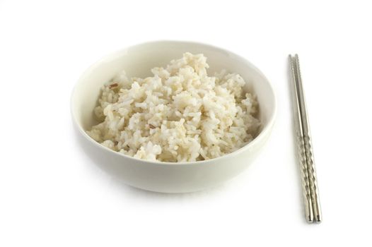 A bowl of cooked brown rice, in an Asian style bowl, with chopsticks isolated on white 