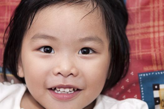 A little Asian girl lying on bed