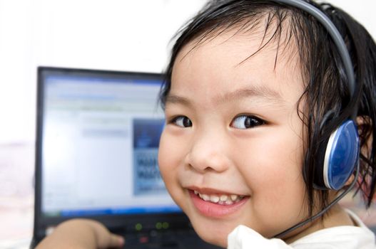 Young preschool girl, listening to music or a video on a laptop computer. 