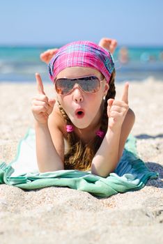 Happy little girl in sunglasses on the beach