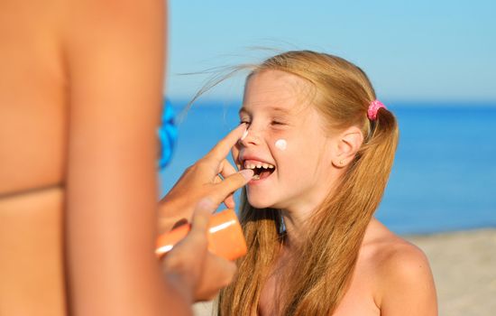 Mother smearing her daughter with sunblock