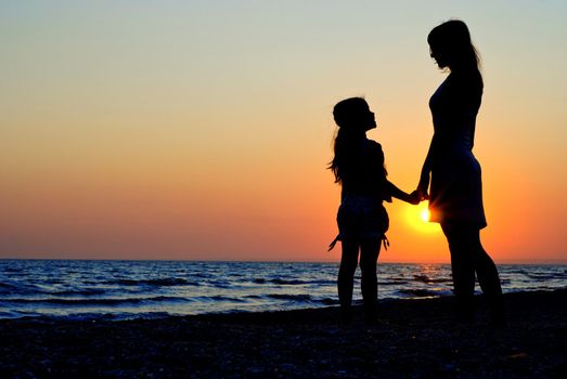 Mother and daughter walking on the beach