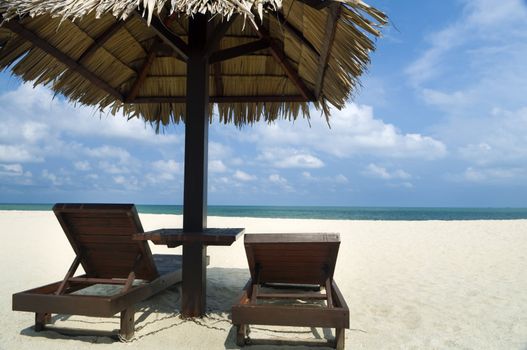Tropical beach with hut and chairs.