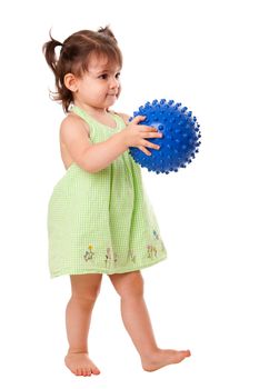 Beautiful cute happy toddler baby girl in green dress walking playing with blue spiky ball, isolated.