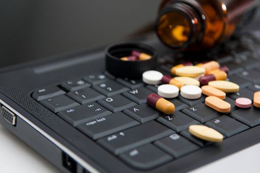 Pills on a laptop, work pressure concept.