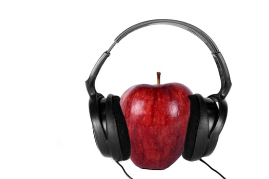 An apple hearing music on the headphones, on white studio background.