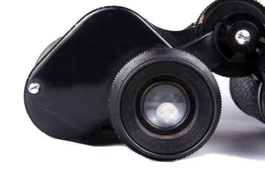 A closeup view of an old binocular lens, on white surface.