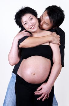 Asian husband kissing his pregnant wife.