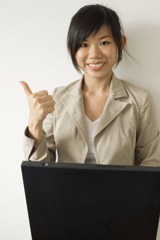 Business woman working with laptop giving an enthusiastic thumbs up 