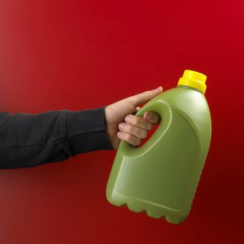 Hand with plastic bottle on red background