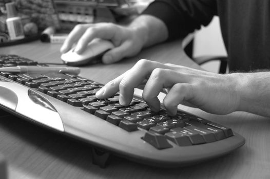 male hand typing on black keyboard, black and white image