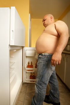 Obese male searching his refrigerator for anything to eat.
